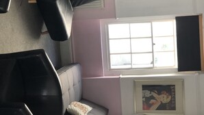 A room with a large window, a sofa, a chair, and a framed picture on the wall. - NO LONGER AVAILABLE FOR RENTAL (Kemptown)