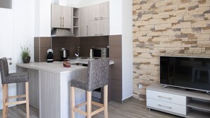 A modern kitchen with a stone accent wall, a built-in microwave, and a bar area with stools. - Stylish Apartment With Balcony & Pool Access Near The Historical Town (Kotor)
