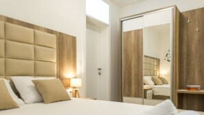 A hotel room with a large bed, a wardrobe with a mirror, and a bedside table with a lamp. - Stylish Apartment With Balcony & Pool Access Near The Historical Town (Kotor)