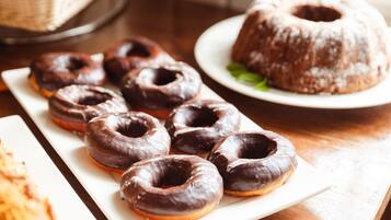 A plate of chocolate-glazed donuts and a bundt cake on a wooden table.