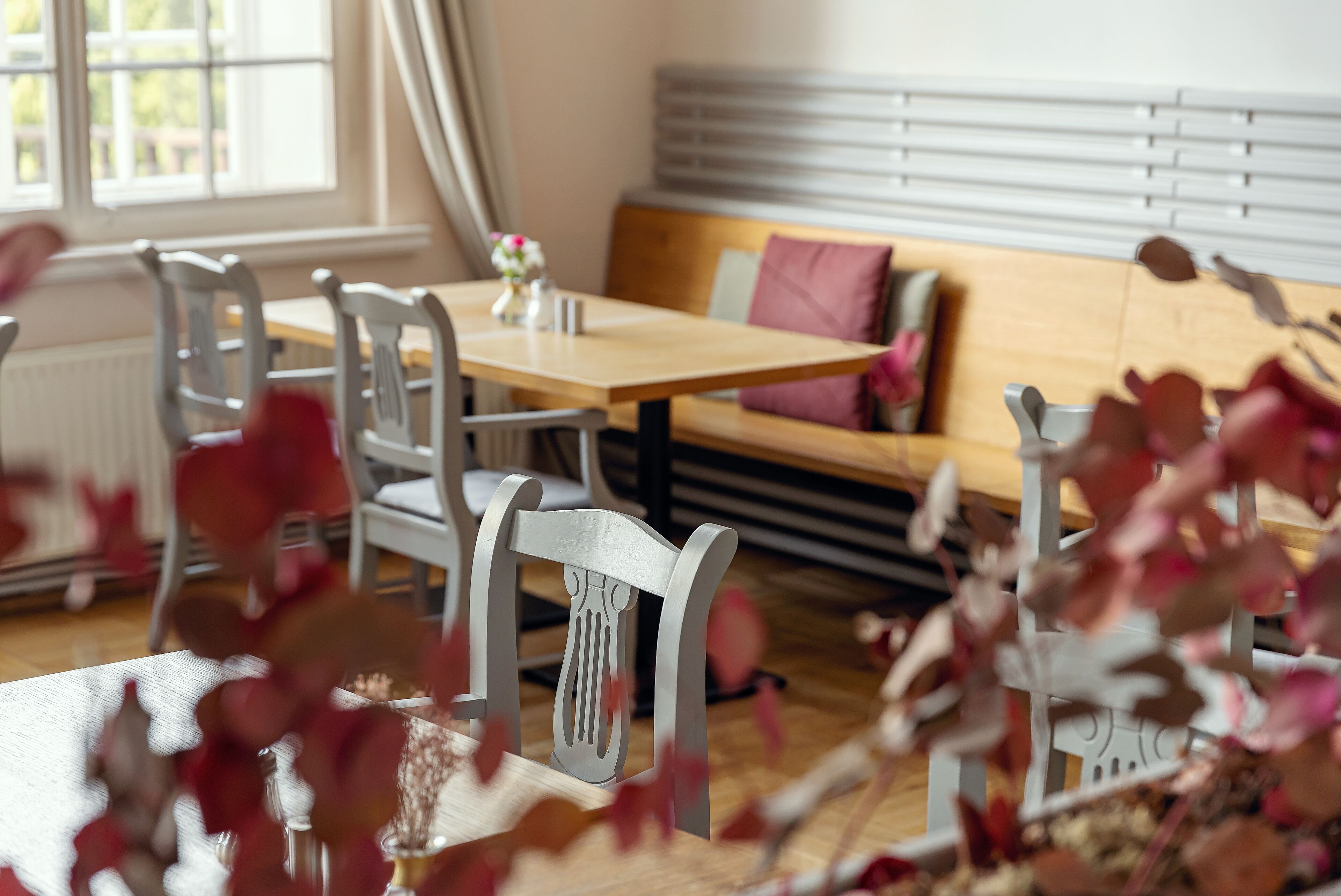 A dining area with a wooden table and chairs, a sofa with cushions, and a window with blinds.