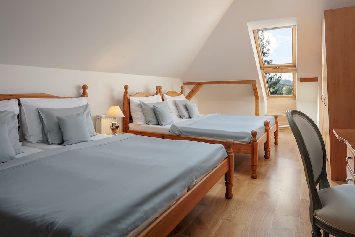 A bedroom with two wooden beds, a skylight, and a wooden desk.