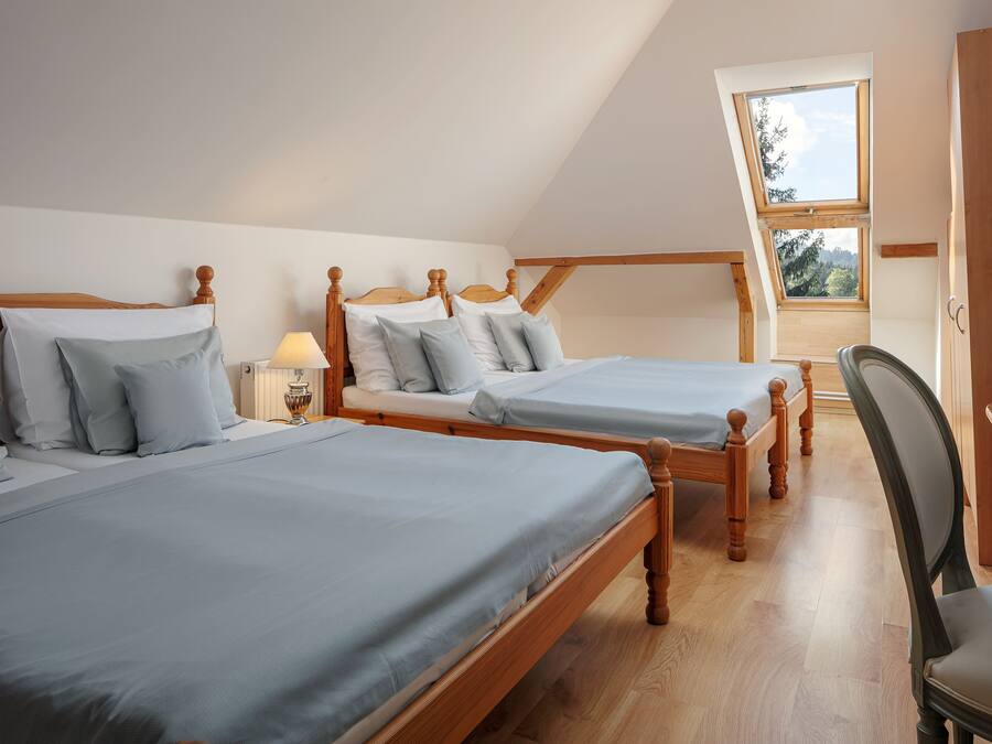 Une chambre à coucher avec deux lits en bois, une lucarne et un bureau en bois.