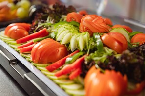 Una barra de ensaladas con diversos vegetales como tomates, pepinos y lechuga.