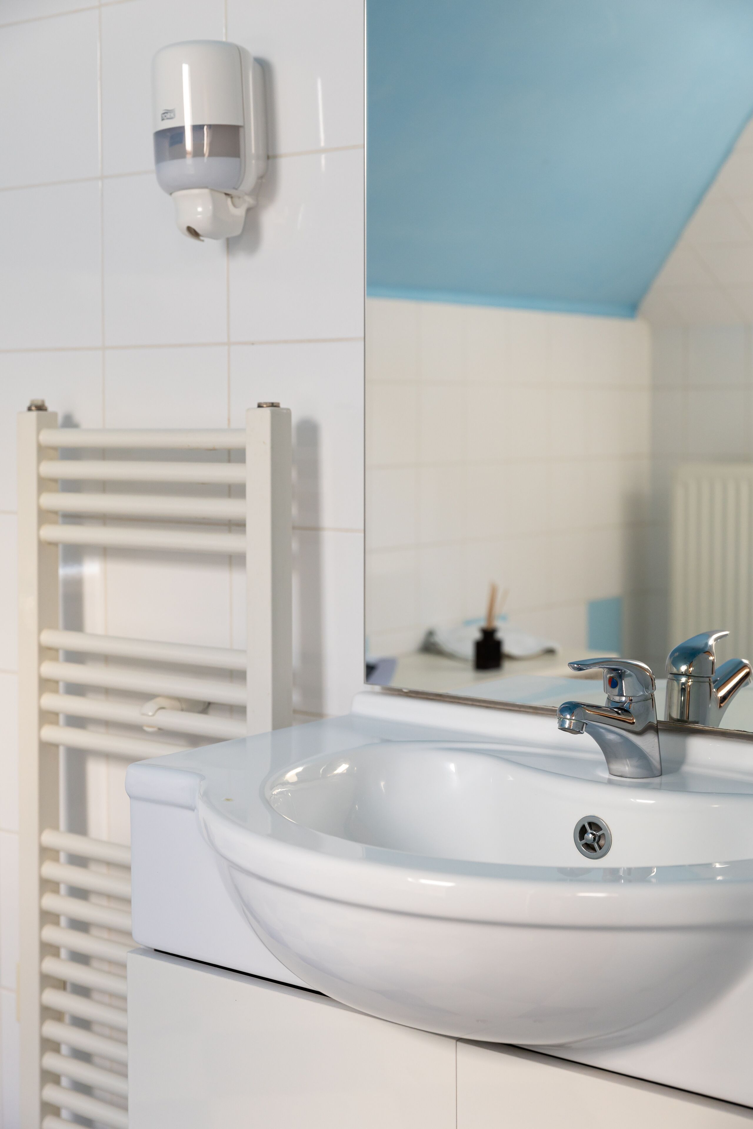 A bathroom with a white sink, a mirror, and a towel rack.