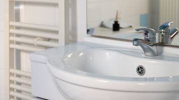 A bathroom with a white sink, a mirror, and a towel rack.