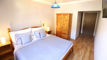 A bedroom with a bed, wooden wardrobe, and a door.