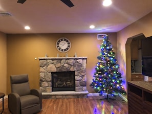 A living room with a stone fireplace, a Christmas tree, and a clock on the wall. - Gorgeous Villa in Pocono nr Ski Slopes, Camelback, Kalahari w Games Rm & Hot tub (Pocono Summit)