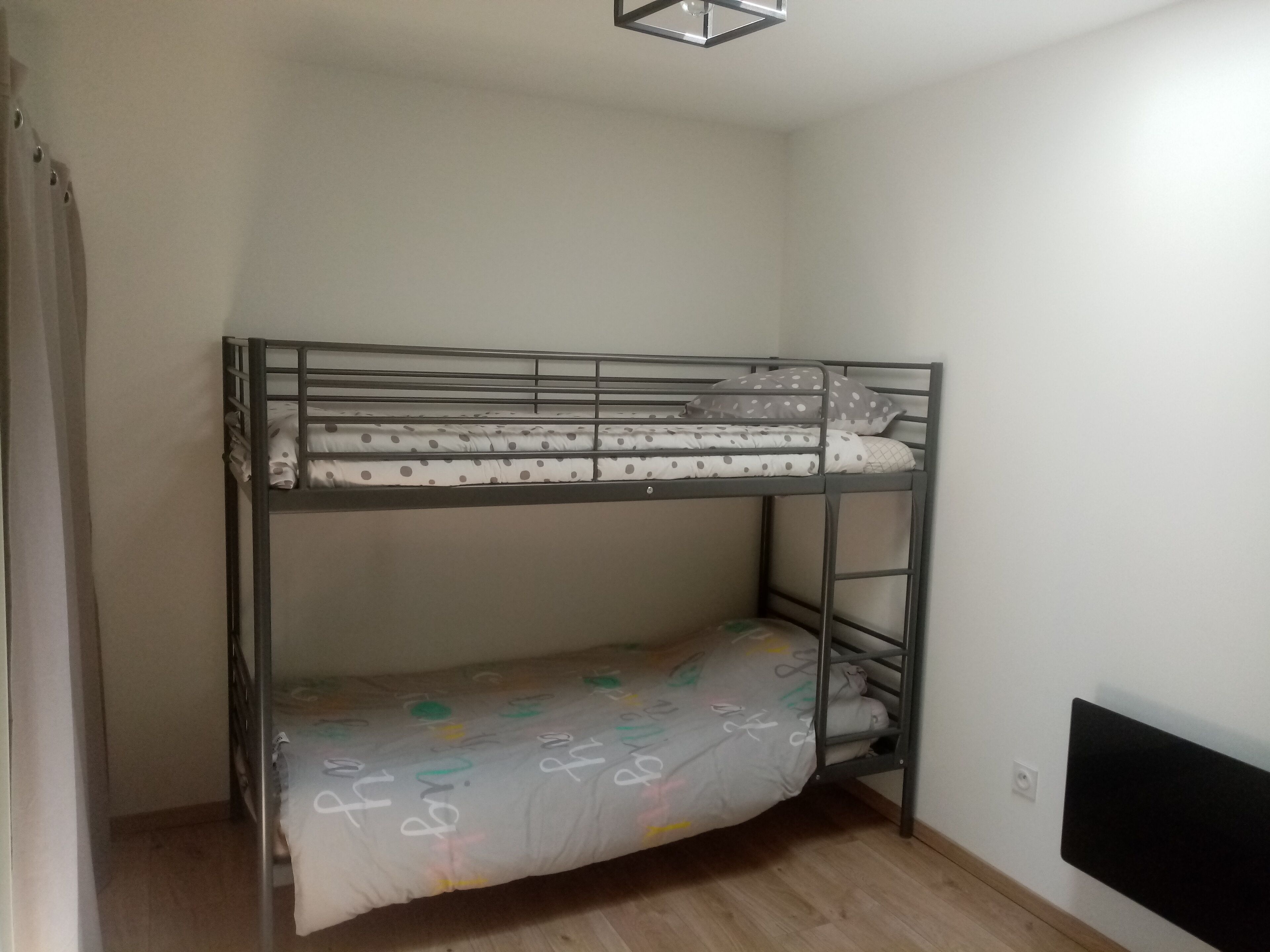 Ein Etagenbett mit einem punkter Matratze und einem unteren Bett mit einer bunten Bettdecke.