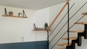 A staircase with wooden steps and black metal railings, flanked by shelves with decorative items and a potted plant.