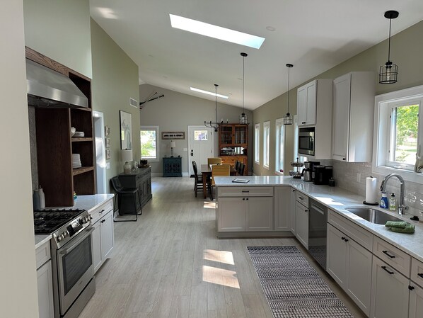 A modern kitchen with a central island, built-in appliances, and a dining area with a view of the outdoors.