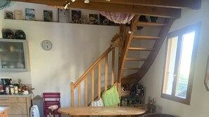 Un accogliente soggiorno con una scala in legno, un'area pranzo e una cucina.