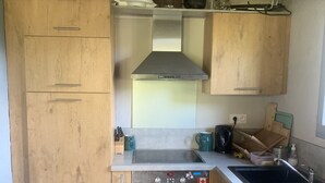 Una cucina con mobili in legno, una cappa in acciaio inossidabile, un forno Bosch e un lavello.
