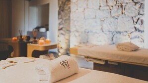 Kylpyhuone, jossa on kiviseinä, hierontapöytä ja pyyhe, jossa on teksti ”GRO TTX SPA”.