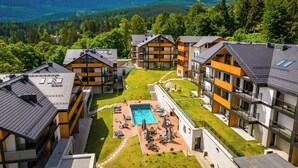 Moderni hotellikompleksi, jossa on useita rakennuksia, suuri uima-allas ja näkymät ympäröiville vuorille.