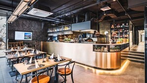 Moderni ravintola, jossa on baarialue, puiset pöydät ja tuolit.