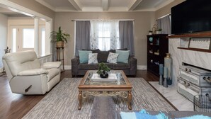 Una sala de estar con sofá, sillón, mesa de centro y televisor.