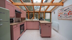 A kitchen with pink cabinets, a green refrigerator, and a wooden ceiling.