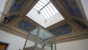 Ein Oberlicht mit Glasdach in einem Raum mit aufwendigen blauen und goldenen Deckenverzierungen.