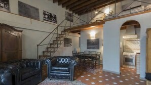 Ein großzügiger Wohnbereich mit Ledersofa, einem gemusterten Teppich und einer Treppe, die in eine obere Etage führt.