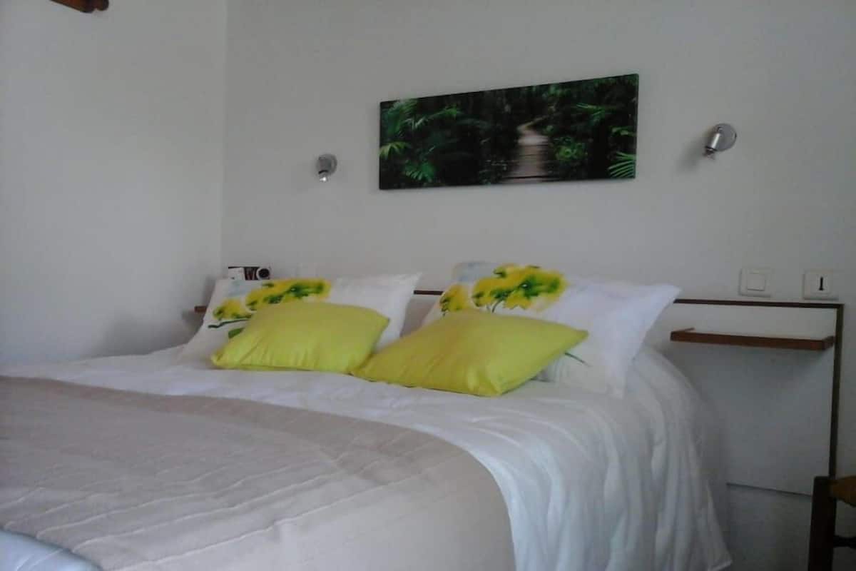 Ein Schlafzimmer mit einem Bett, weißer Bettwäsche und zwei gelben Kissen.