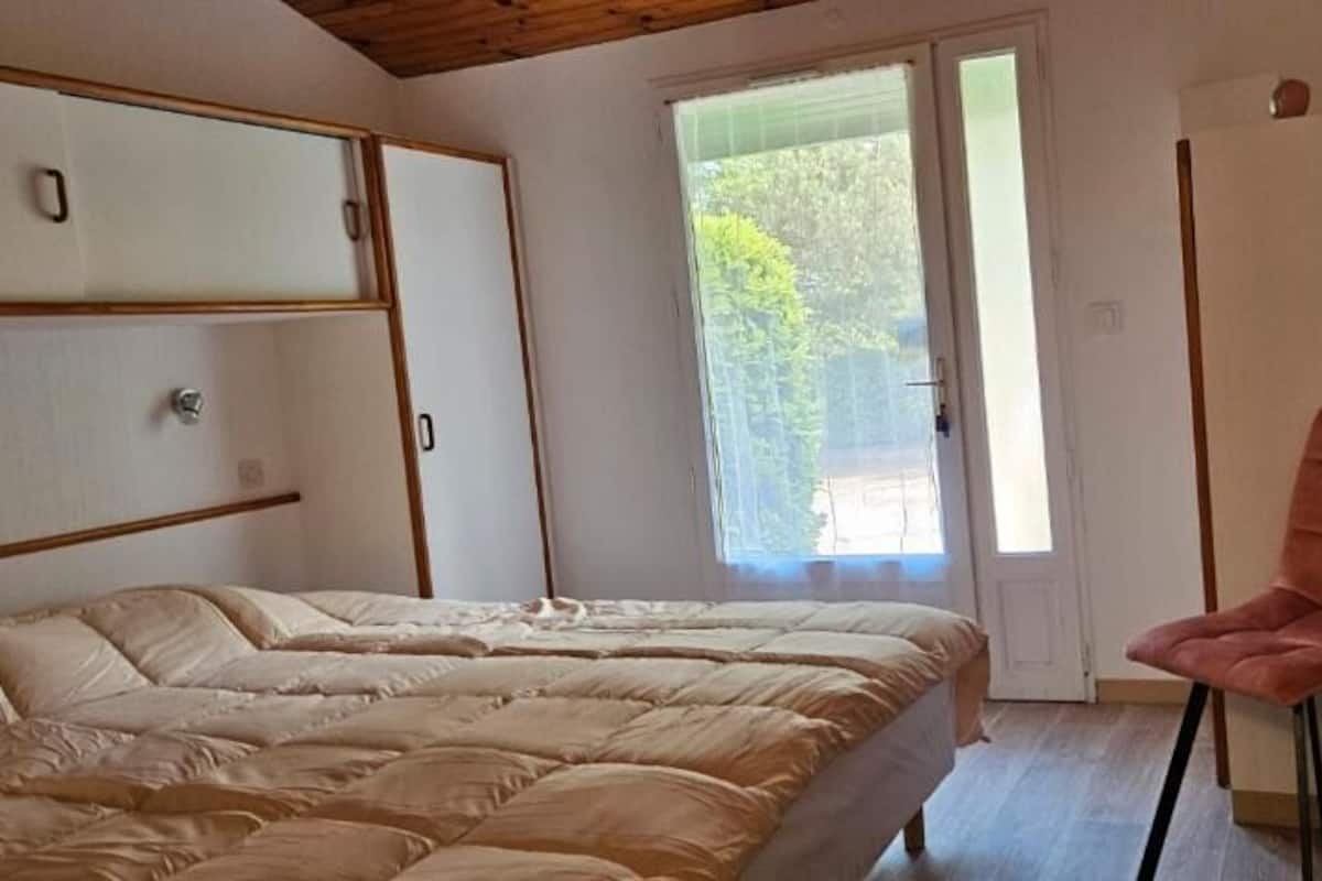 Ein Schlafzimmer mit Bett, Stuhl, Kleiderschrank und einer Tür zum Balkon.