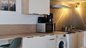 A compact kitchen with a washing machine, a microwave, and a coffee maker. - Le Hameau de la Courbière (Tarascon-sur-Ariege)
