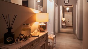 A hallway with a lamp, a bicycle decoration, and a small table with a lamp. There is a door at the end of the hallway. - Downtown Loulé  (Loulé)