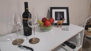 A white table with a wine bottle, two wine glasses, a bowl of fruit, a framed picture, and a small figurine. - Downtown Loulé  (Loulé)