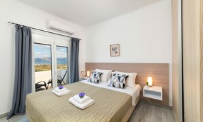 A hotel room with a bed, a nightstand, a potted plant, and a view of the landscape. - Cretan Sunset Villa | Heated Pool (Georgioupoli)