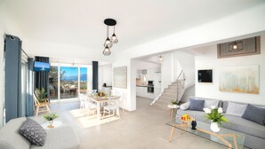 A modern living room with a sofa, a glass coffee table, and a dining area with a table and chairs.