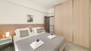 A hotel room with a double bed, a nightstand with a lamp, a wooden headboard, a painting on the wall, and a sliding door.