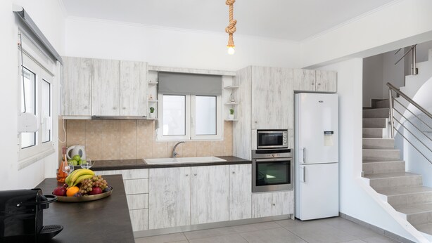 A modern kitchen with white cabinetry, a built-in oven, a microwave, and a refrigerator.