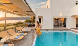 A swimming pool with lounge chairs and a person standing by the pool.