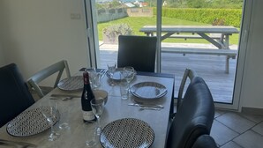 A dining table set for four with a view of a grassy area and a wooden deck outside.