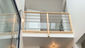 A modern interior with a glass balcony, a white door, and a wicker chair.