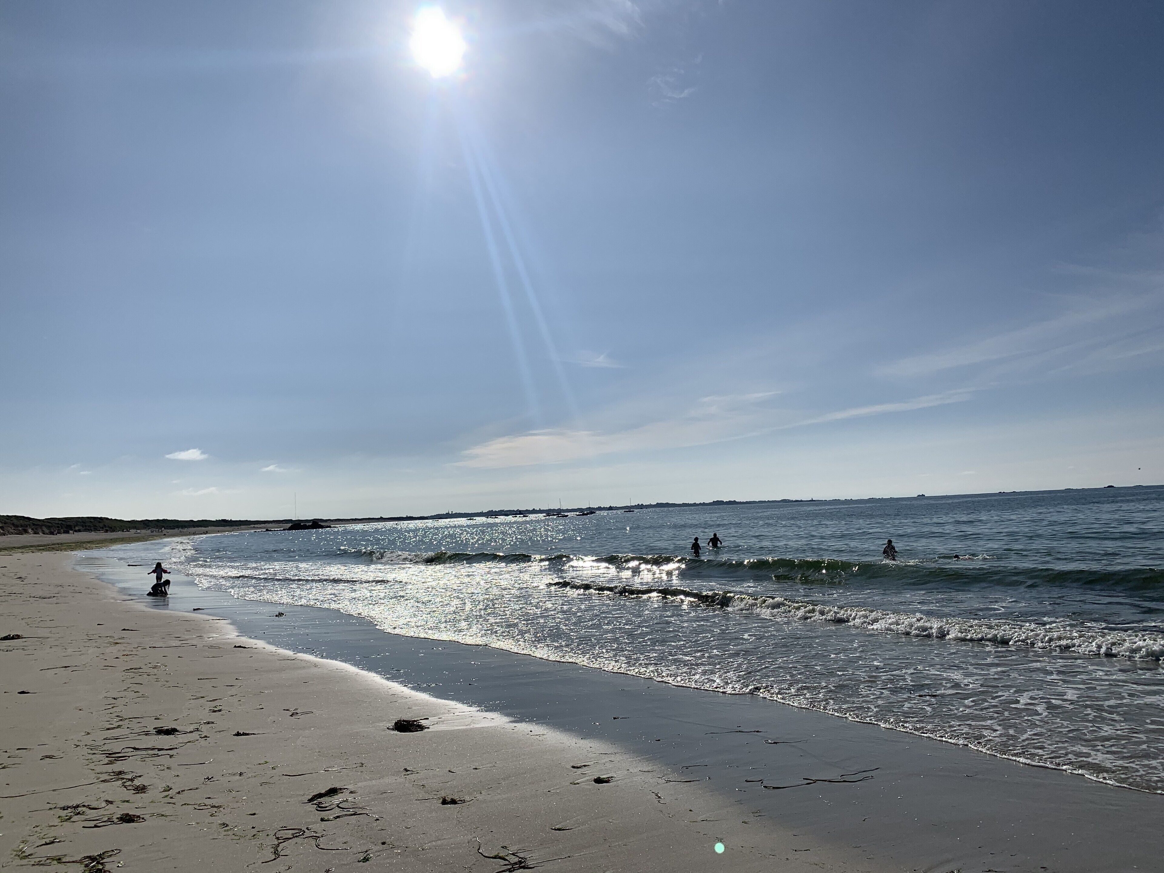 Een strand met heldere lucht en zonlicht op het water.