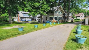Une rue résidentielle bordée de maisons, avec une allée gravillonnée et des plantes en pot.
