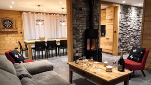 Un salon chaleureux avec un canapé, un coin repas avec des chaises, une table avec des boissons et un mur en pierre.