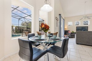 Relax in a stylish living space with a glass dining table, comfortable sofa, and flat-screen TV.