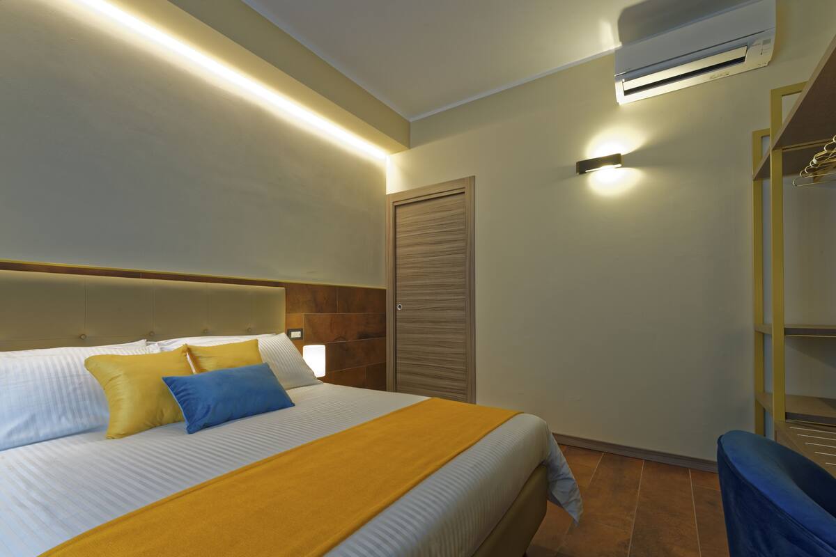 A hotel room with a bed, a wardrobe, and a chair.