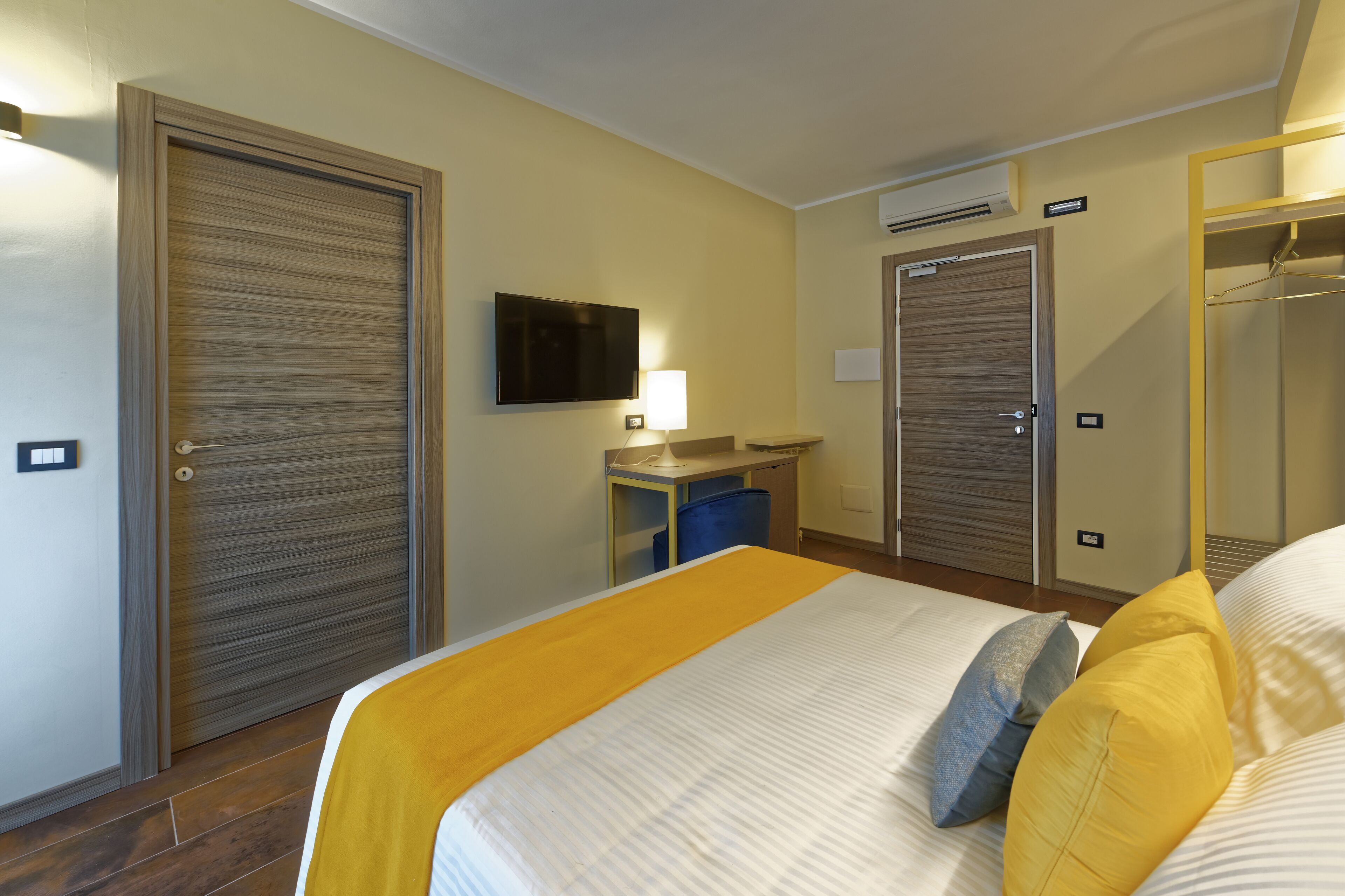 A hotel room with a bed, a TV, a desk, and a wardrobe.