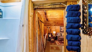 A wooden interior with a hallway leading to a seating area, a wall-mounted towel rack, and a visible door. - Farm - Animals - Barn - Gazebo - Fire Pit - 2xKing (Willington)