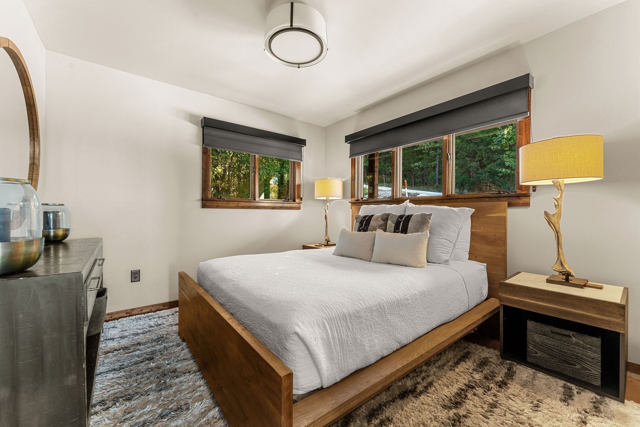 A bedroom with a bed, bedside tables, a lamp, a mirror, and a window.