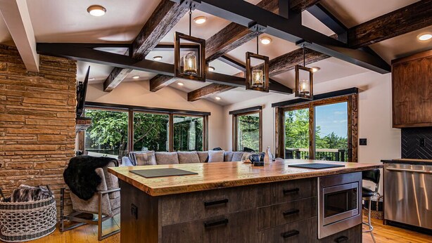 A spacious kitchen with a large island, wooden beams, and large windows offering views of the outdoors. - Near Big Cedar-Walkable Fun-Lake View-Hot Tub-Modern Luxury Decor-Free Attraction Tickets! (Ridgedale)