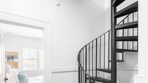 A modern interior with a spiral staircase, wooden flooring, and a white wall with a window. - B2 at Saint Philip Square, One Block to King, Second Floor Private Porch (Charleston)