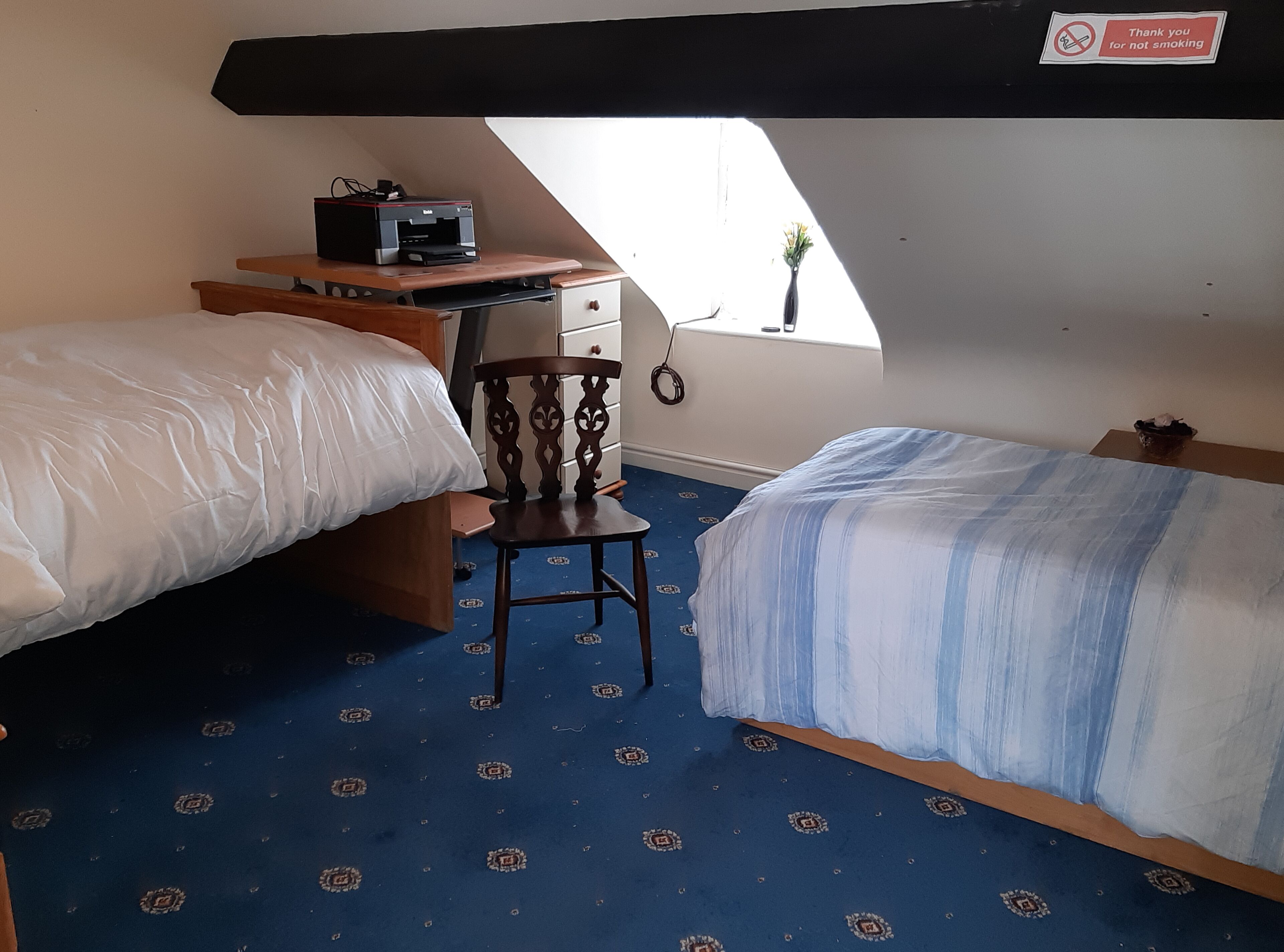 Un dormitorio con dos camas, un escritorio con una impresora, una silla y una ventana con vistas.