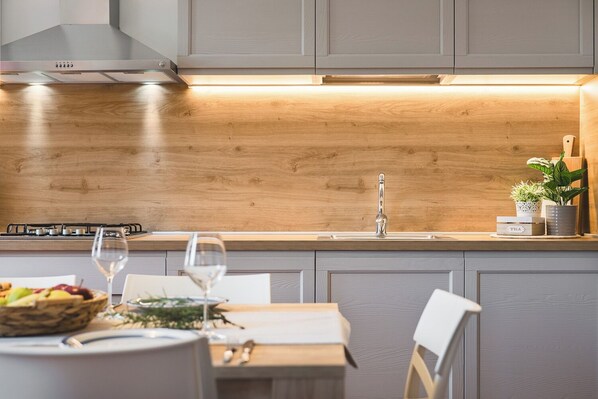 Eine moderne Küche mit Holztischplatte, Edelstahlspüle und Essbereich mit Tisch für zwei Personen.
