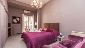 A bedroom with a large bed, a bedside table, a lamp, and a chandelier. - Ripetta Deluxe Terrace (Rome)