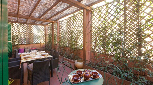 An outdoor patio with wicker furniture, a table set for two, and a tray with teapot and cups. - Ripetta Deluxe Terrace (Rome)